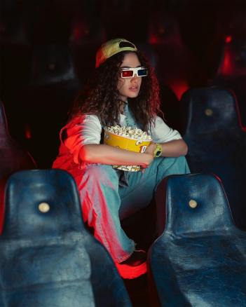 a woman sitting in a movie theater with popcorn